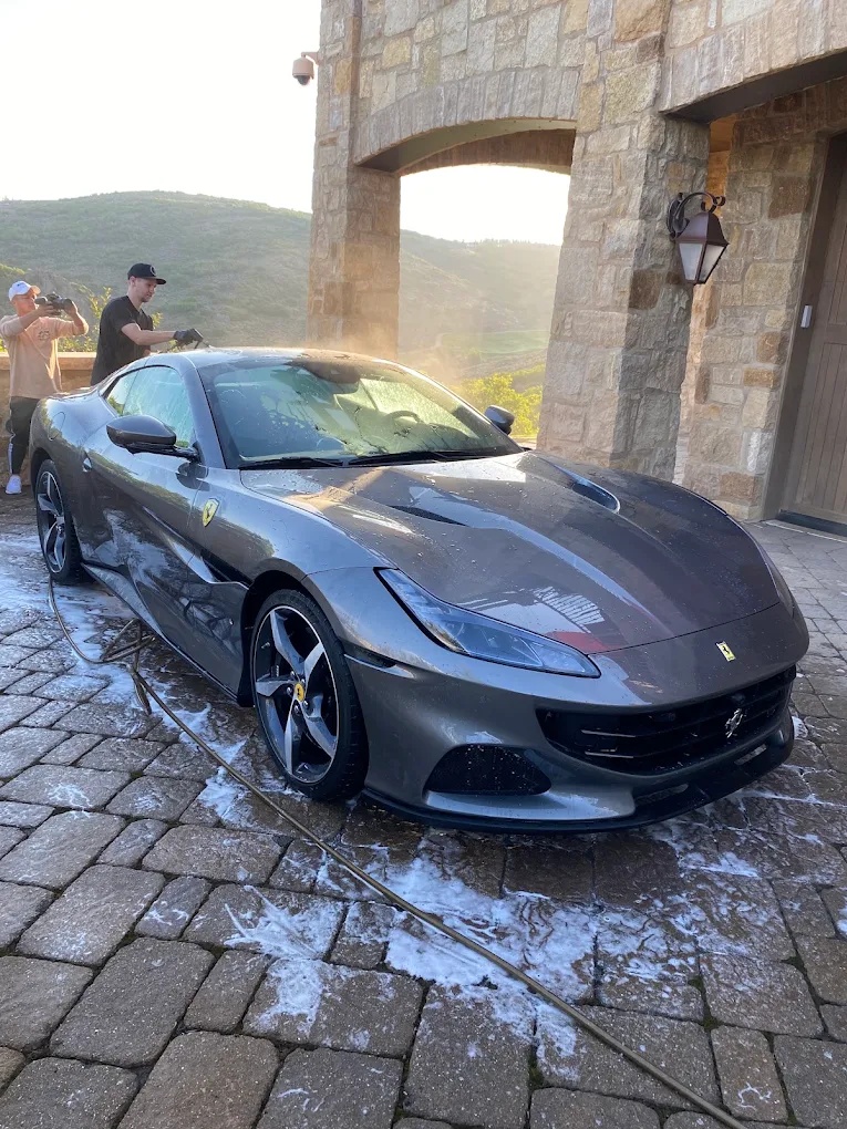 Detailers hand washing a gray Ferrari Portofino in a Phoenix driveway